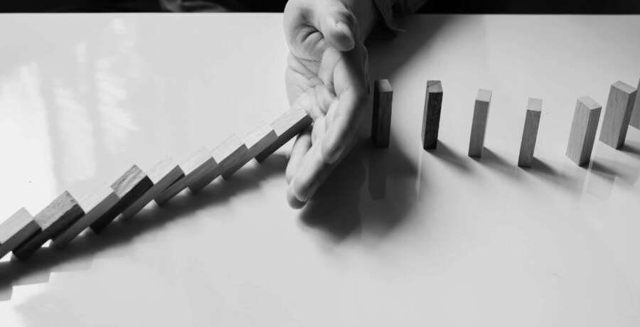 businessman hand stop dominoes continuous toppled or risk with copyspace